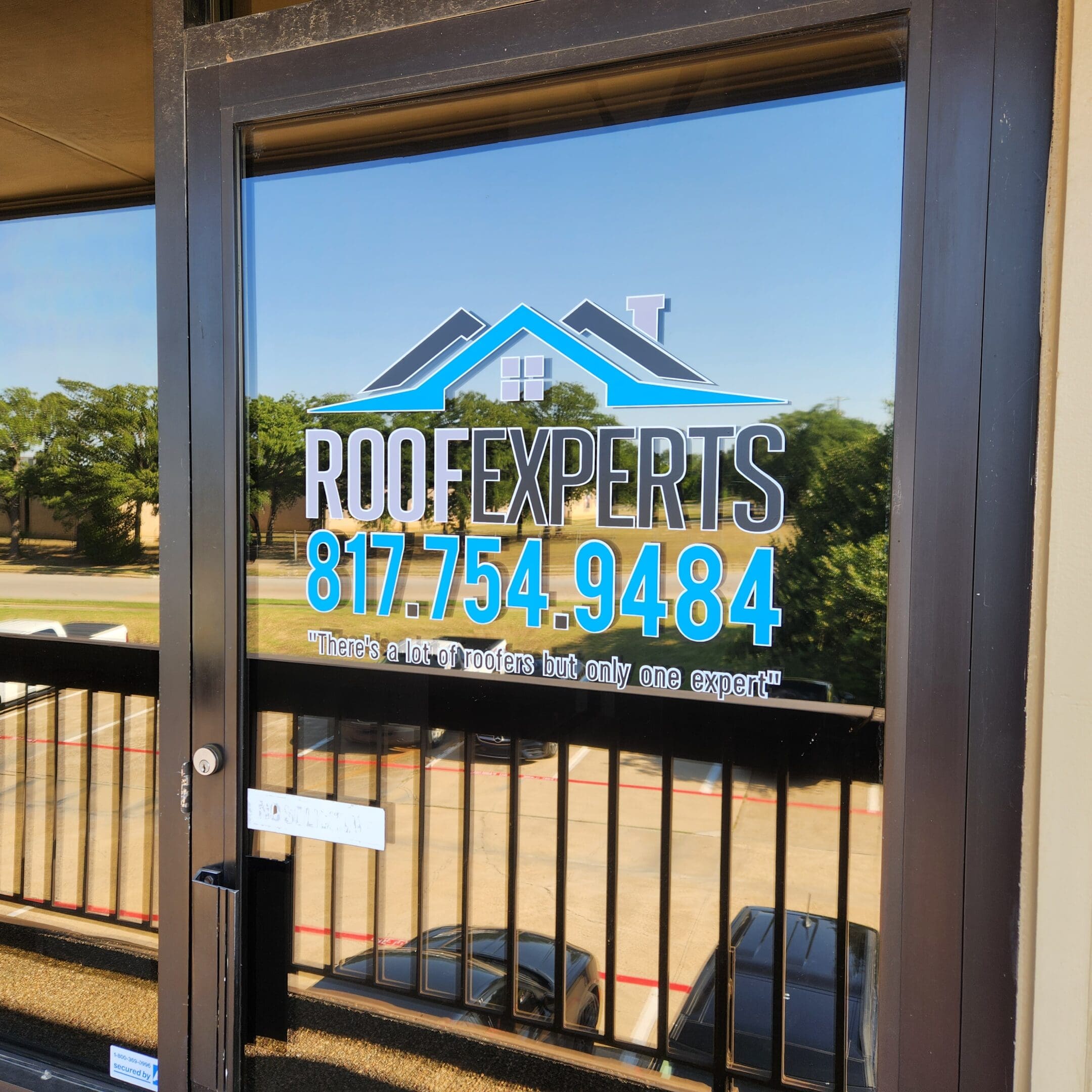 A window with the company logo of roof experts.