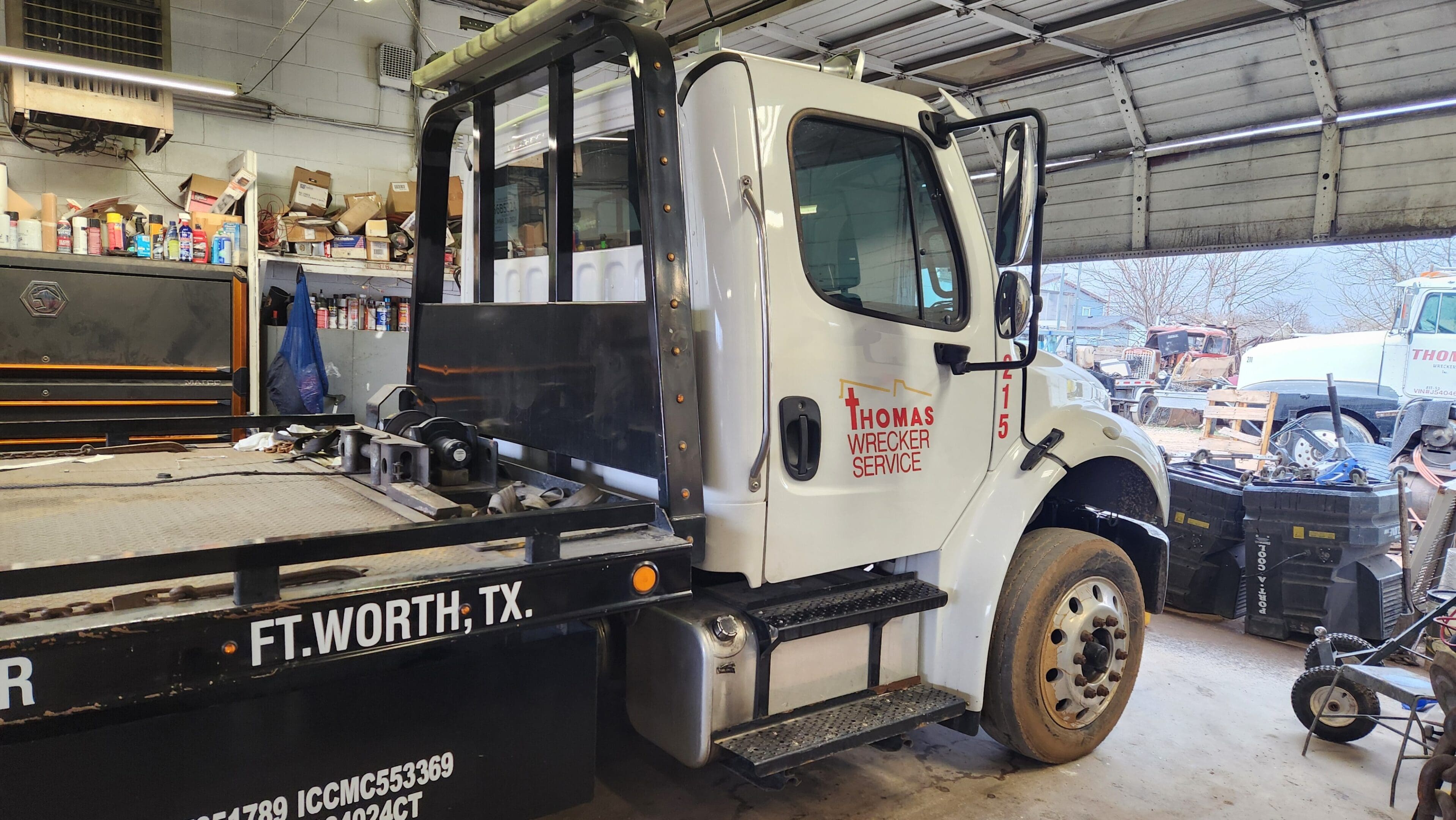 A tow truck parked in a garage with the door open.