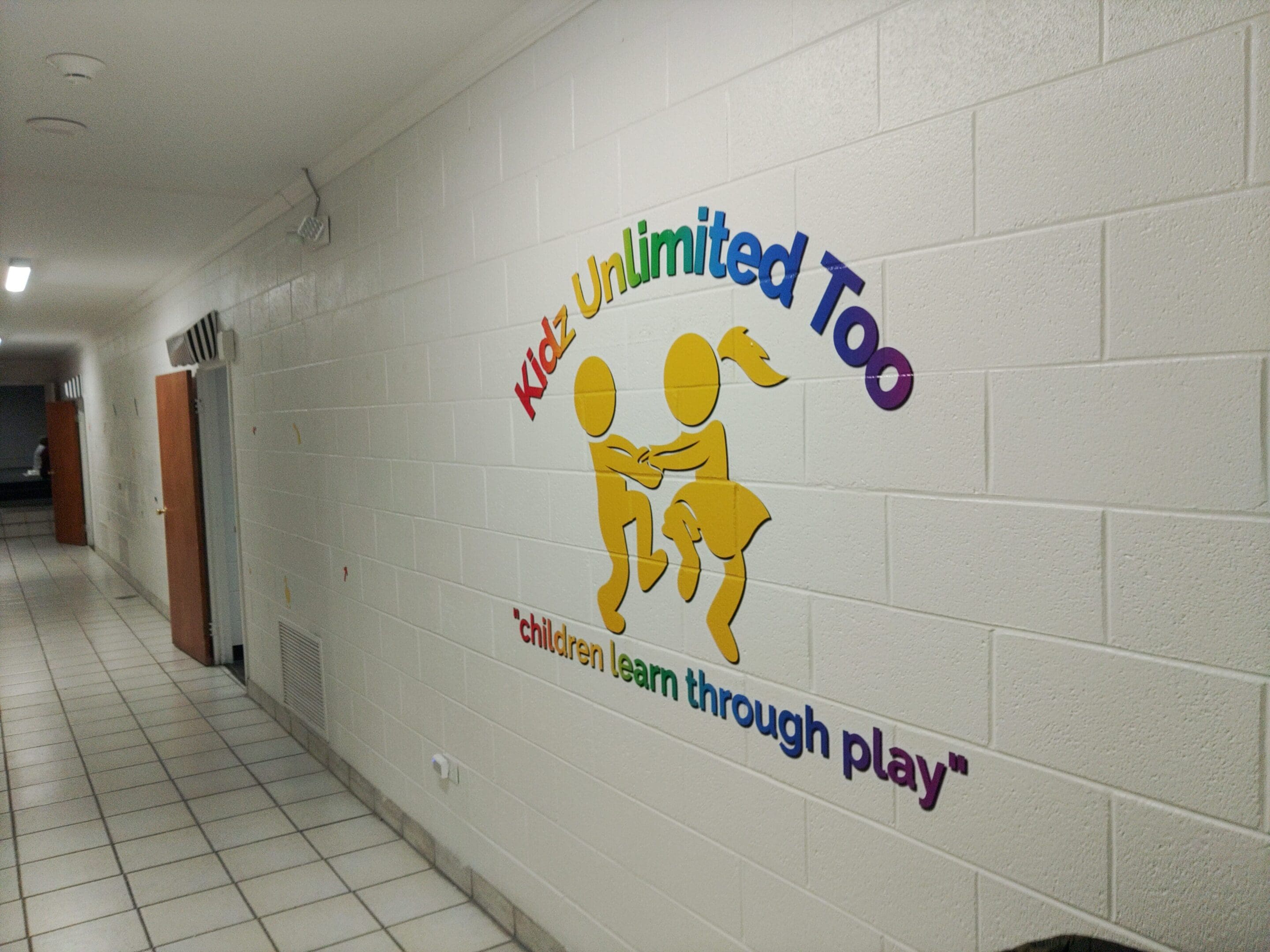 A wall with the words " kids unlimited too " written on it.