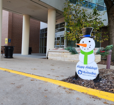 A snowman sitting in the middle of a sidewalk.