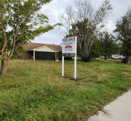 A sign in front of a house that says for sale.